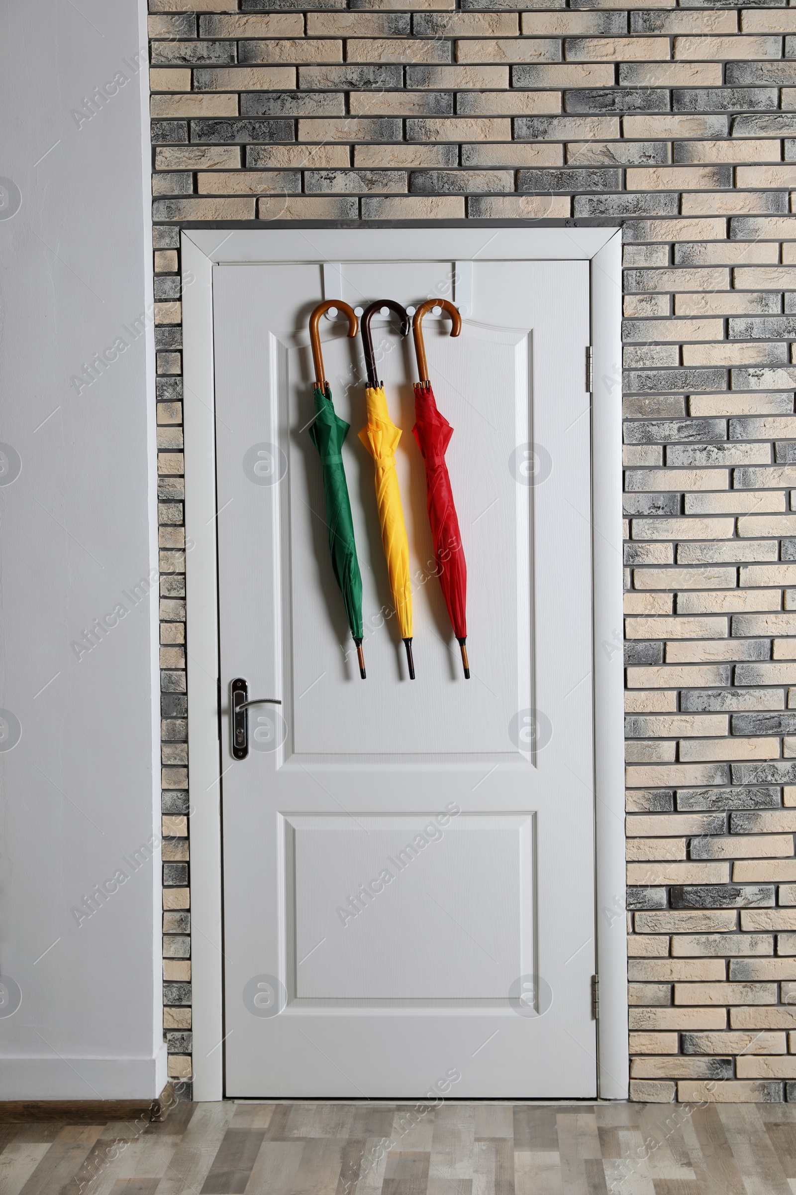 Photo of Colorful umbrellas hanging on door in brick wall