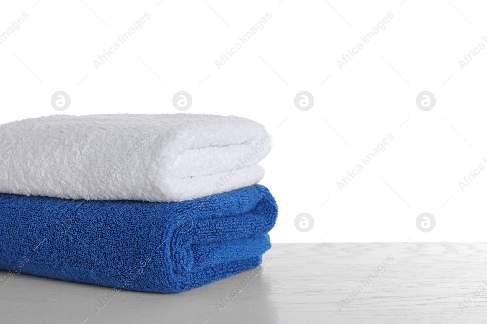 Photo of Stacked soft towels on table against white background