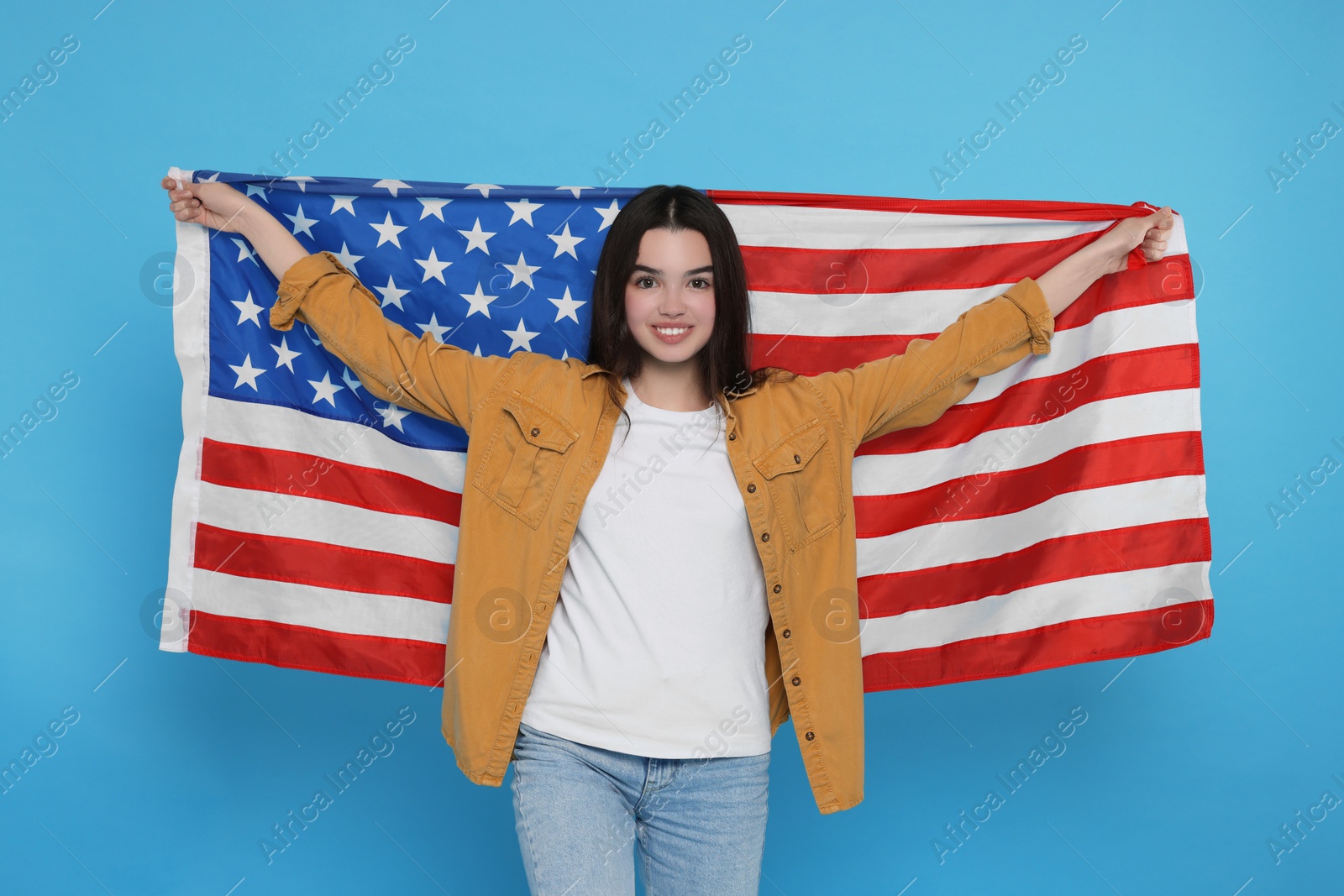 Photo of 4th of July - Independence Day of USA. Happy girl with American flag on light blue background