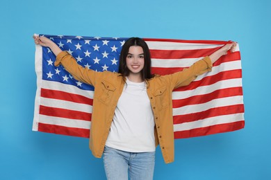 4th of July - Independence Day of USA. Happy girl with American flag on light blue background