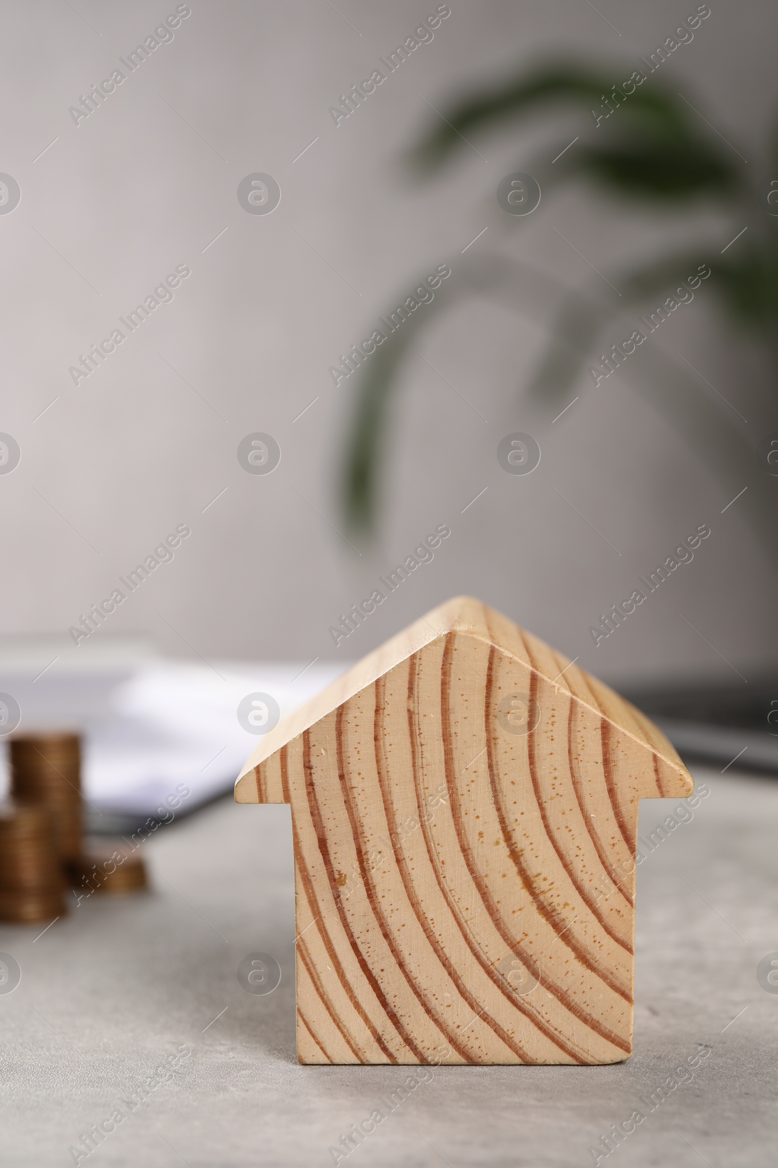 Photo of Wooden house model on grey table, closeup. Financial savings