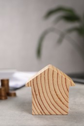 Photo of Wooden house model on grey table, closeup. Financial savings