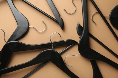 Black hangers on brown background, top view