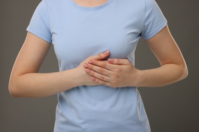 Photo of Woman having heart attack on grey background, closeup
