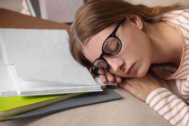 Young tired woman sleeping near books on couch, closeup
