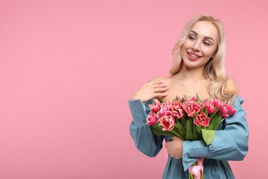 Happy young woman with beautiful bouquet on dusty pink background. Space for text