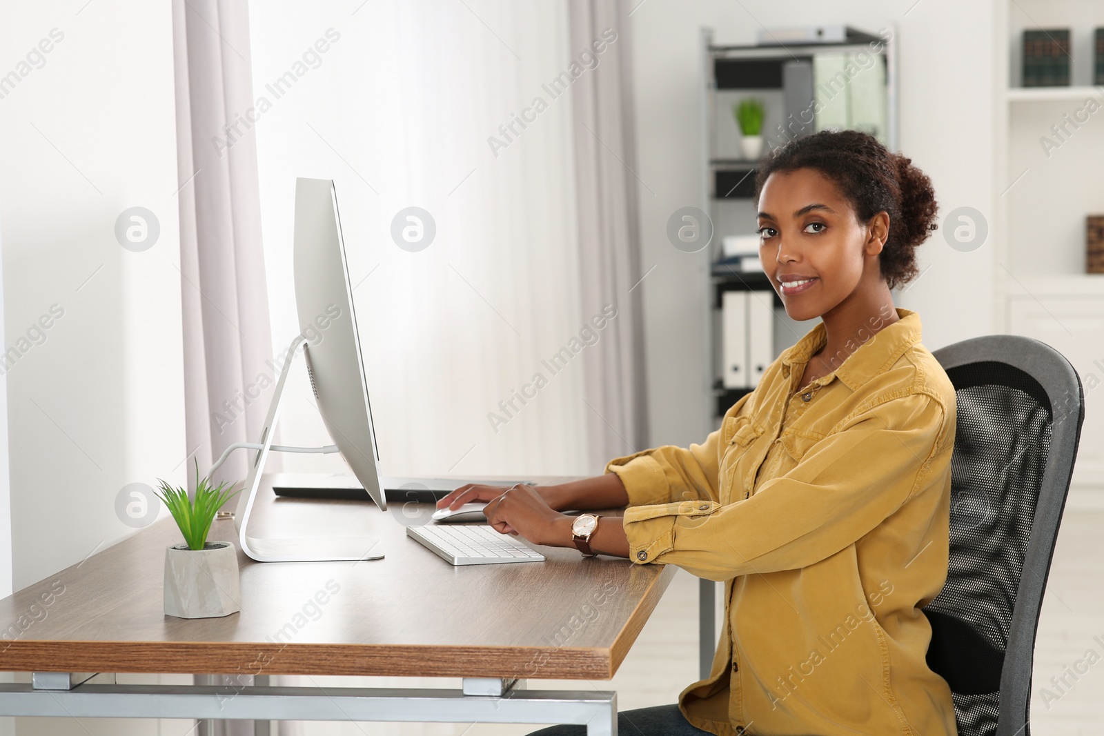 Photo of Smiling African American intern working with computer at table in office