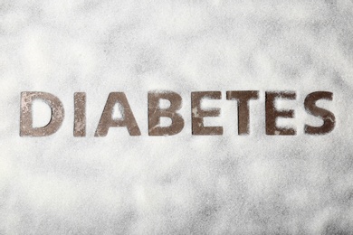 Photo of Silhouette of word DIABETES on scattered sugar, top view