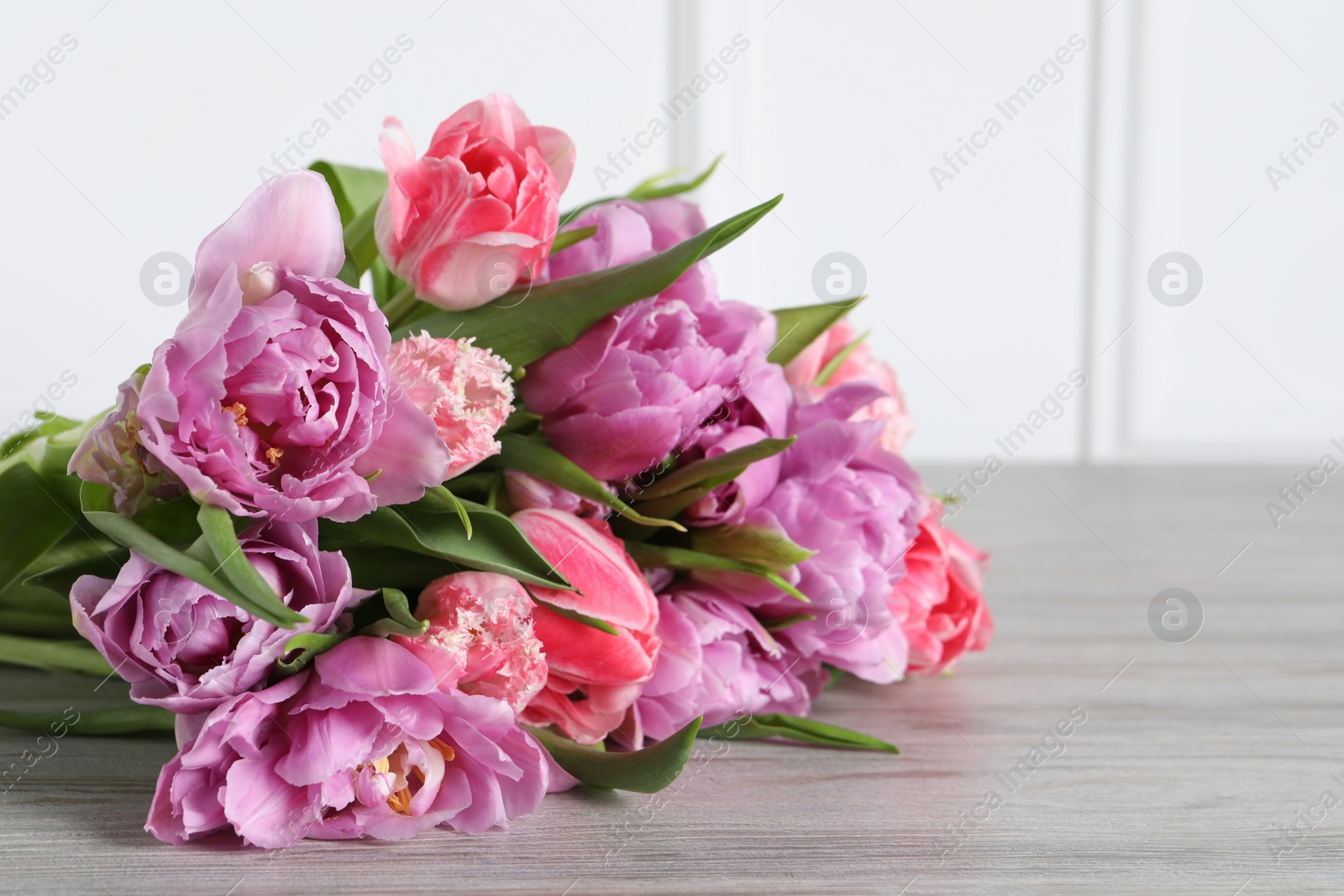 Photo of Beautiful bouquet of colorful tulip flowers on wooden table, closeup. Space for text