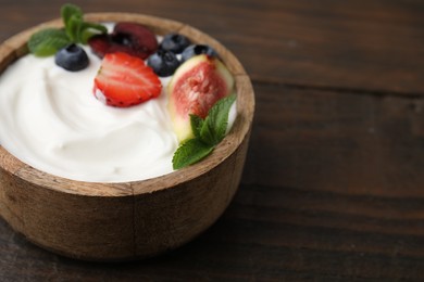 Photo of Bowl with yogurt, berries, fruits and mint on wooden table, closeup. Space for text