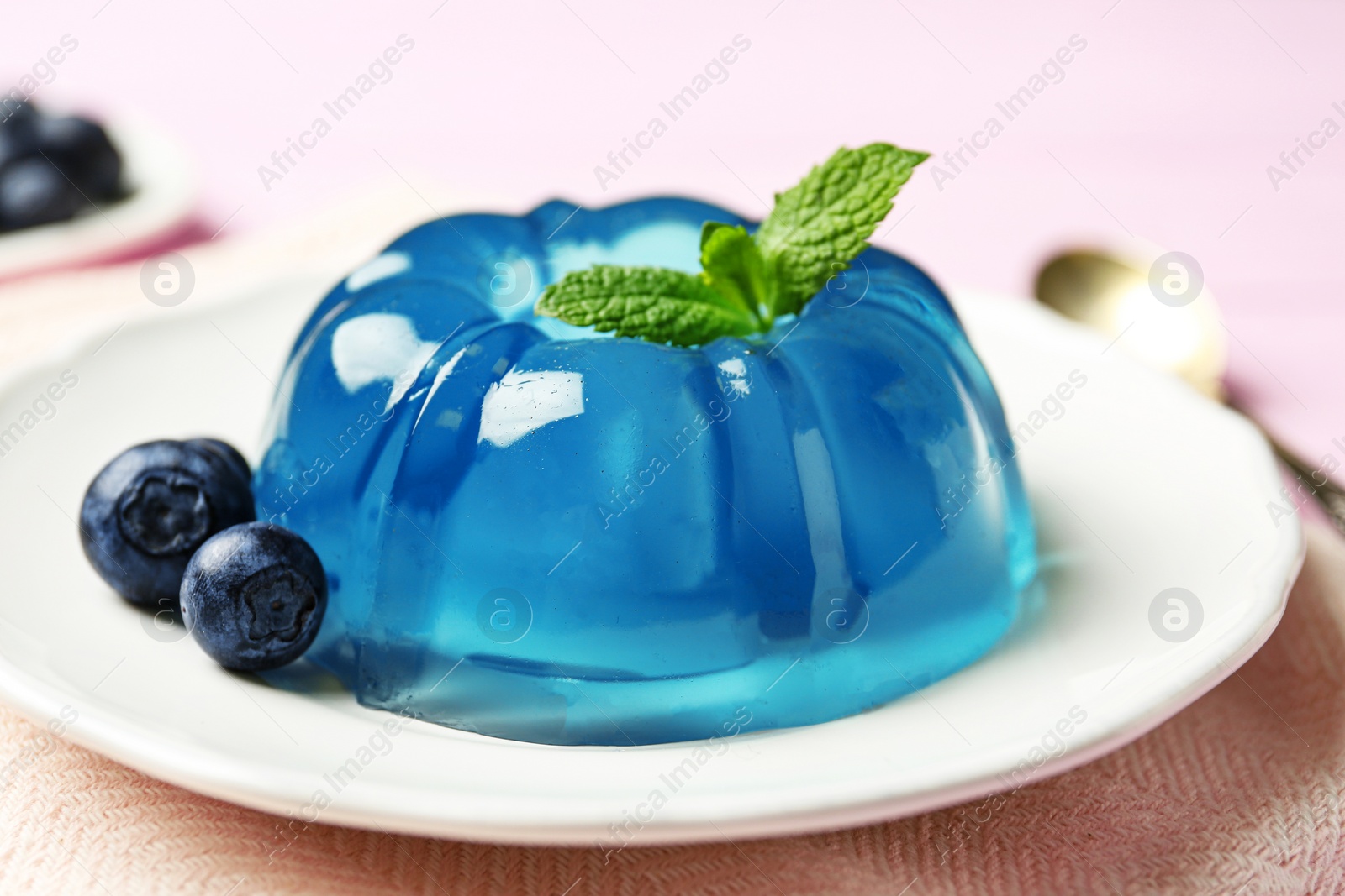 Photo of Plate of delicious blue jelly with berries on pink wooden background, closeup