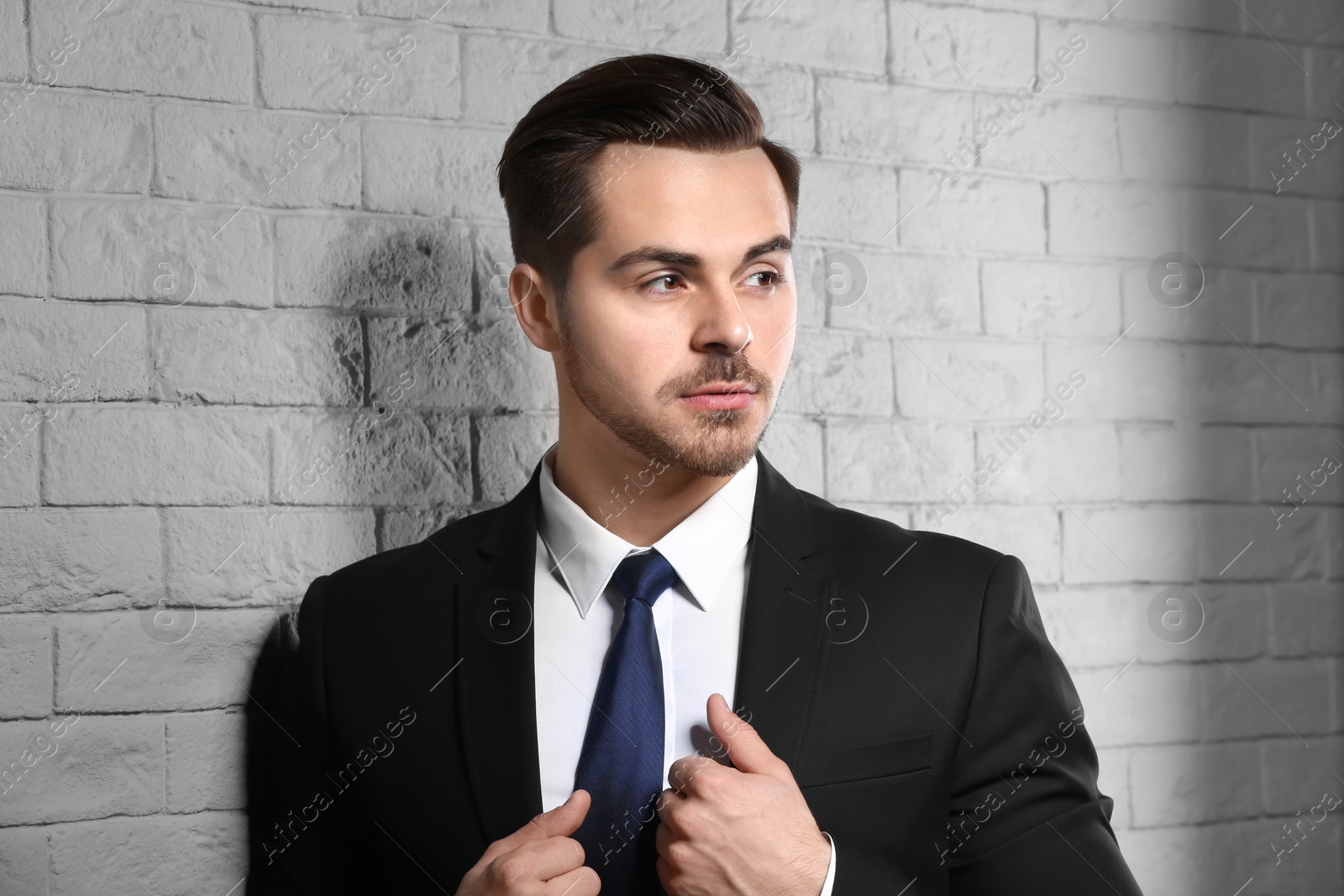 Photo of Portrait of young man with beautiful hair on brick wall background