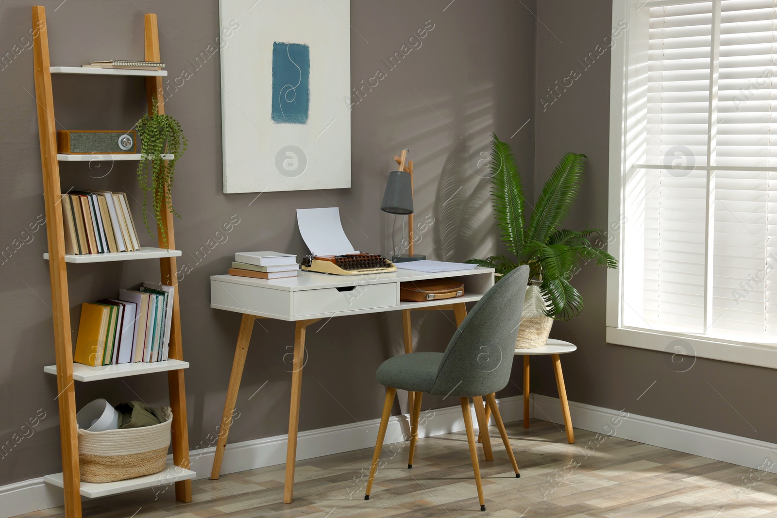 Photo of Comfortable writer's workplace interior with typewriter on desk near grey wall