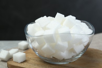 Photo of White sugar cubes in glass bowl on grey table