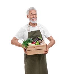 Photo of Harvesting season. Farmer holding wooden crate with vegetables and winking on white background