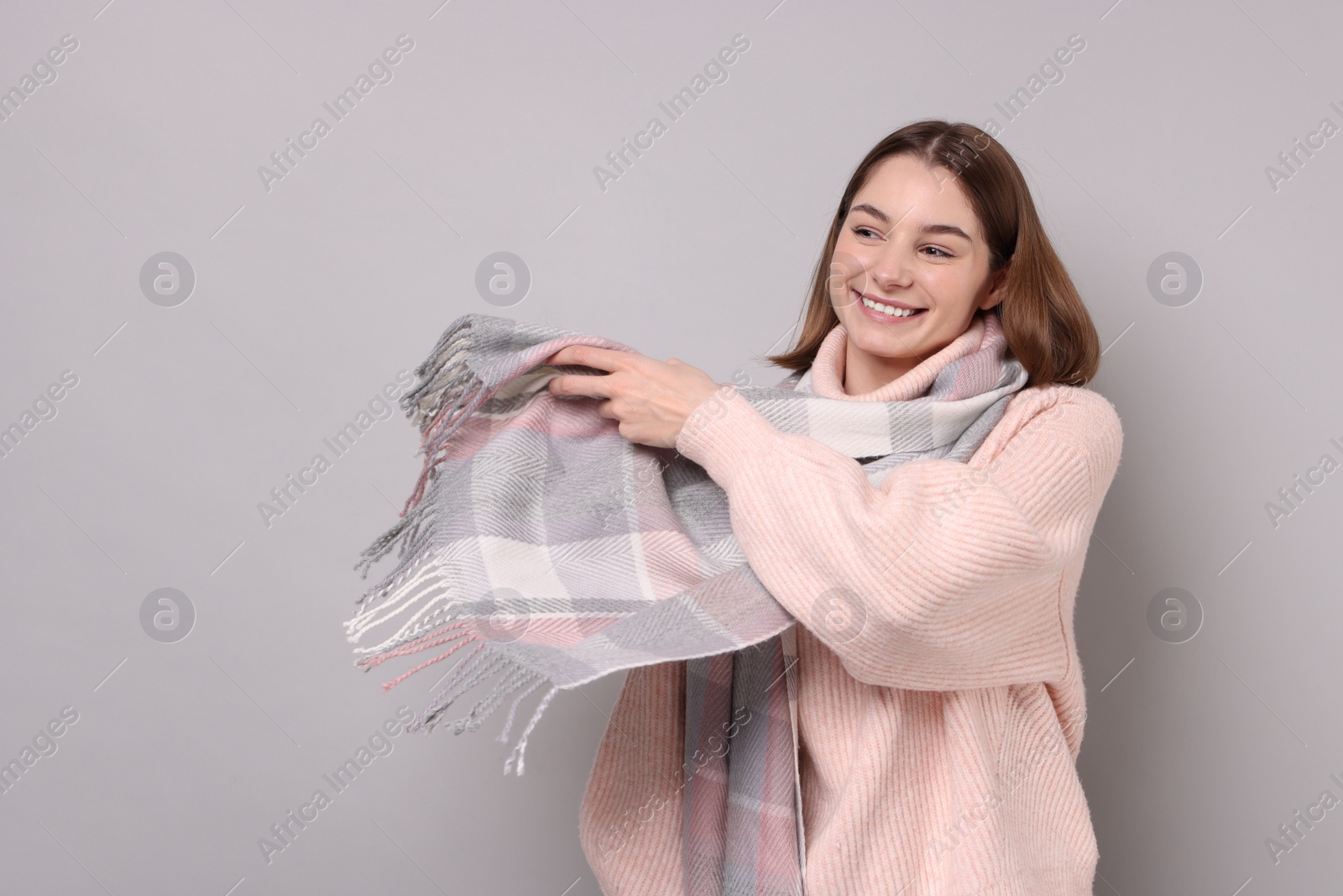 Photo of Beautiful woman in warm scarf on gray background, space for text