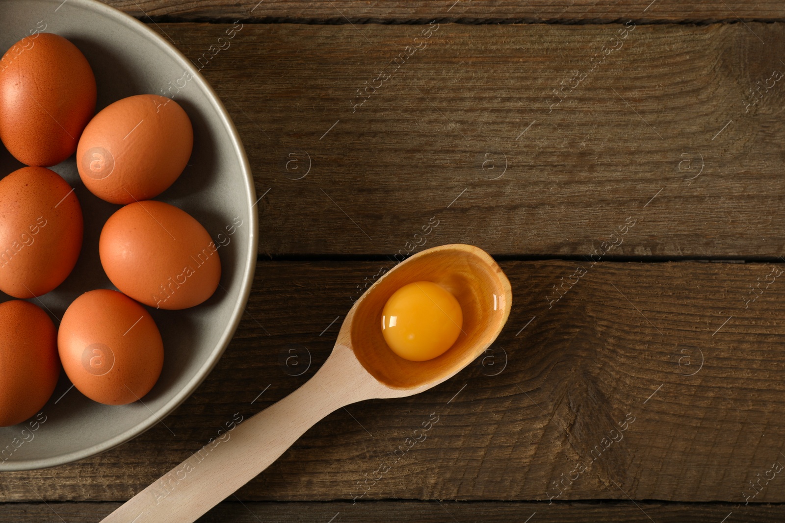 Photo of Raw chicken eggs on wooden table, flat lay. Space for text