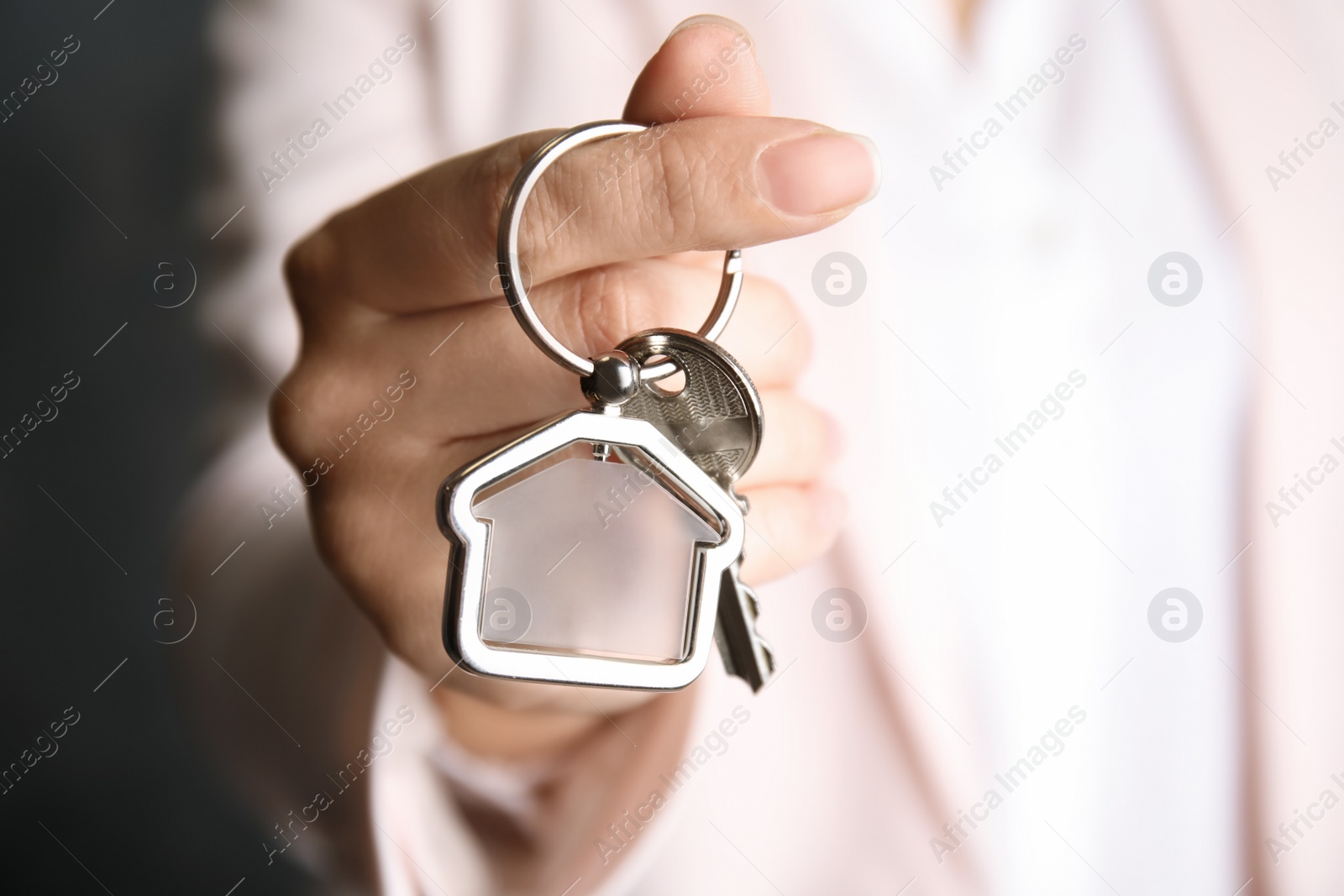 Photo of Young woman holding house key with trinket, closeup