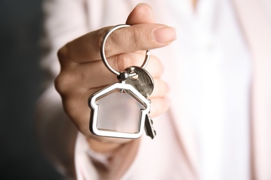 Photo of Young woman holding house key with trinket, closeup