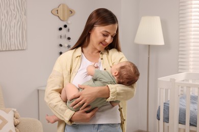 Mother holding her sleeping newborn baby in child`s room