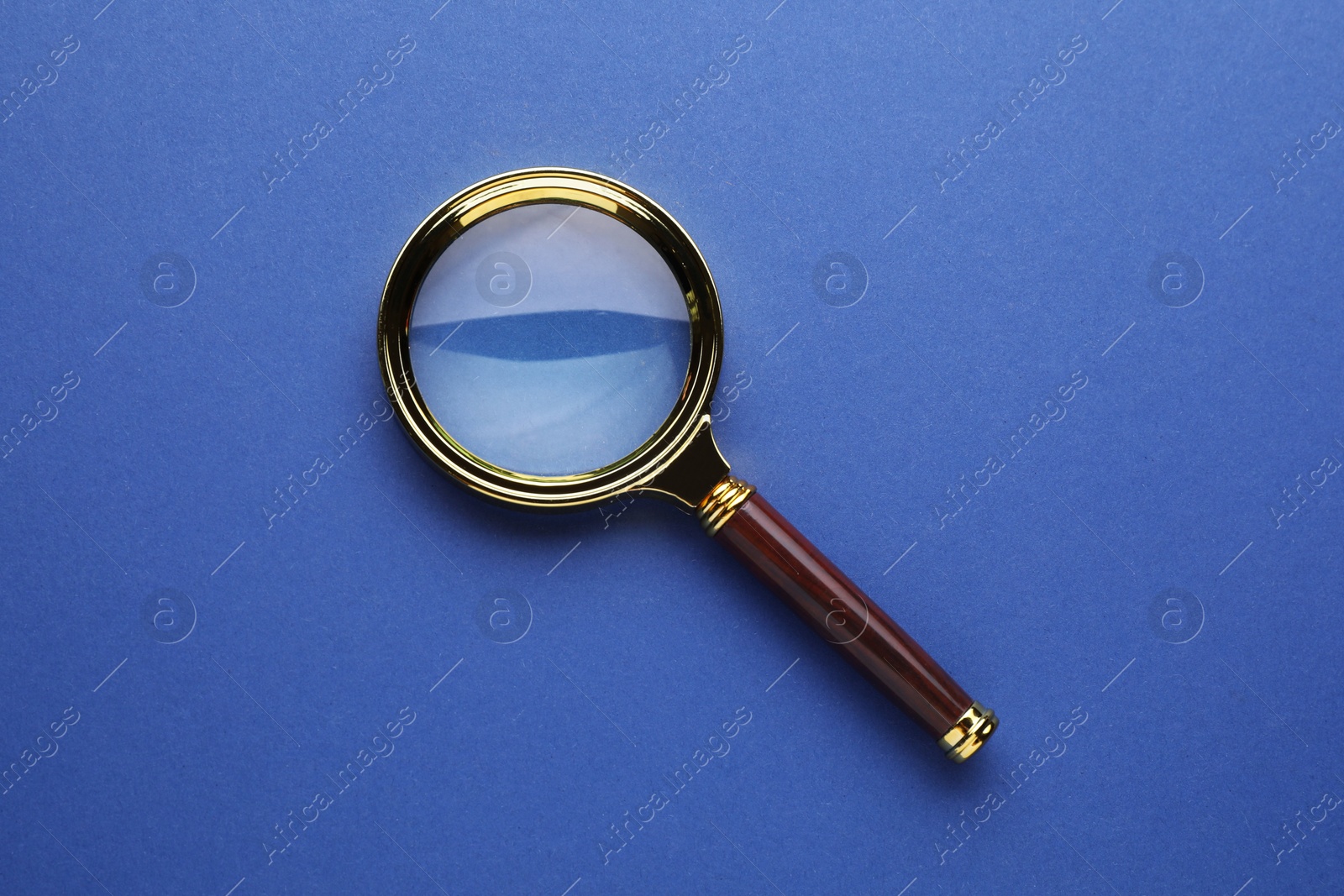 Photo of Magnifying glass on blue background, top view