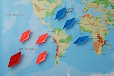 Photo of Colorful paper boats on world map, flat lay