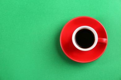Photo of Cup of tasty coffee on green background, top view. Space for text