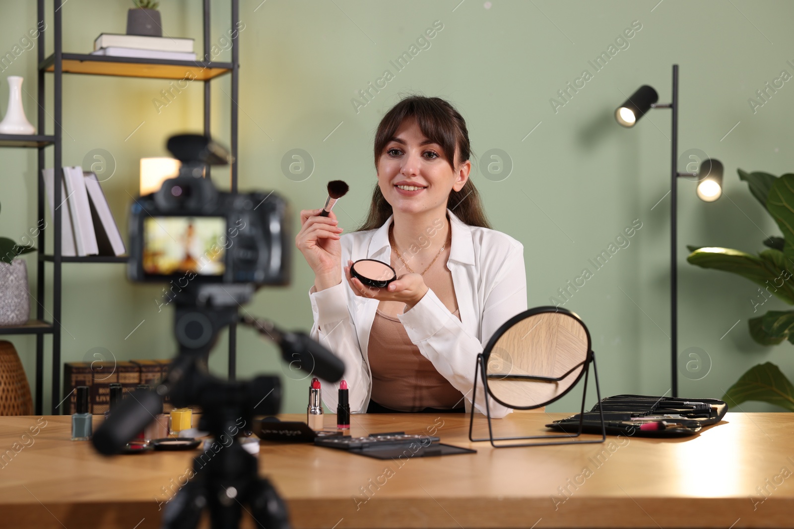 Photo of Smiling beauty blogger recording makeup tutorial at home