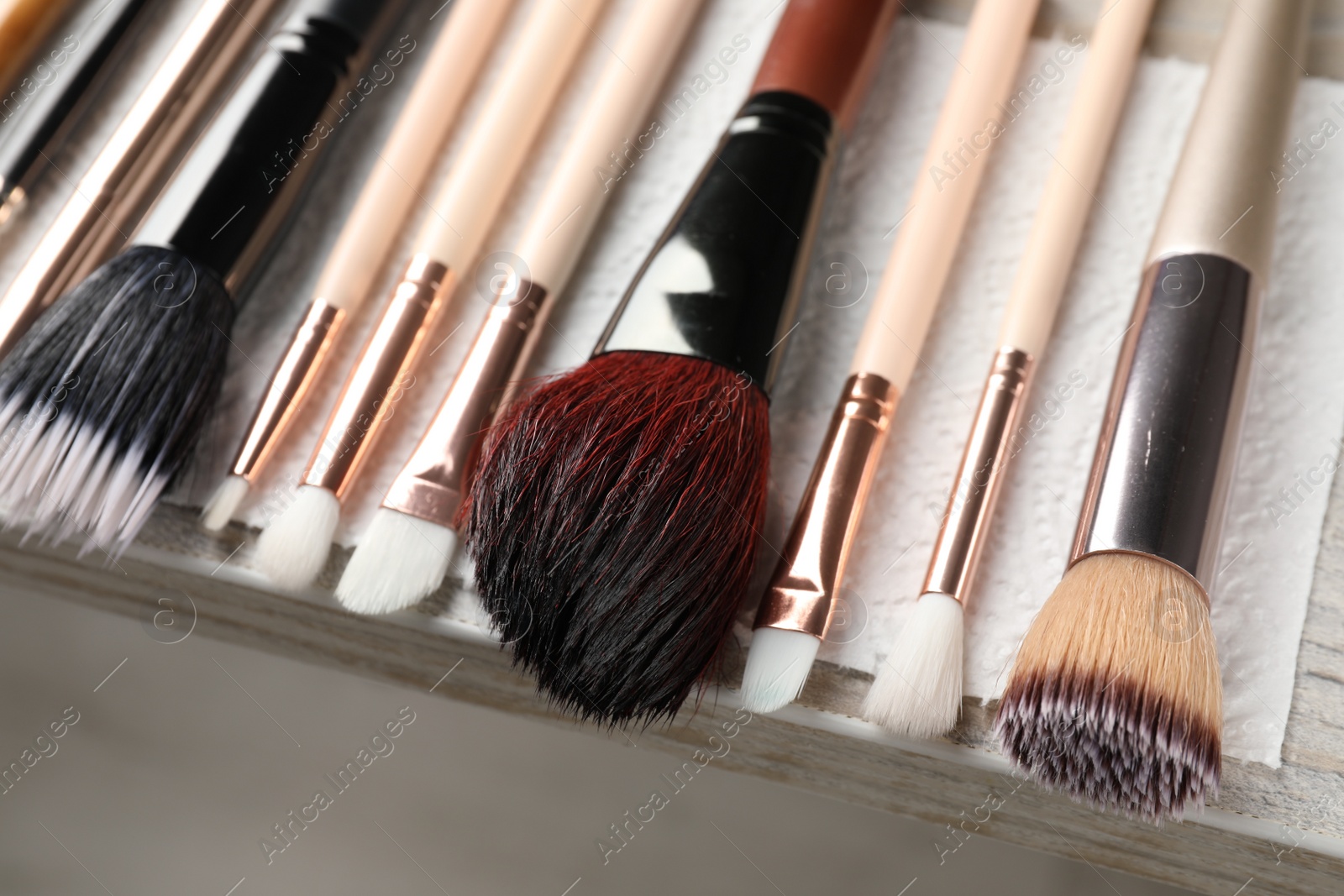 Photo of Set of different makeup brushes drying after cleaning on table, closeup