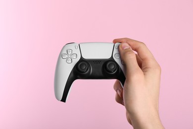 Photo of Man using wireless game controller on pink background, closeup
