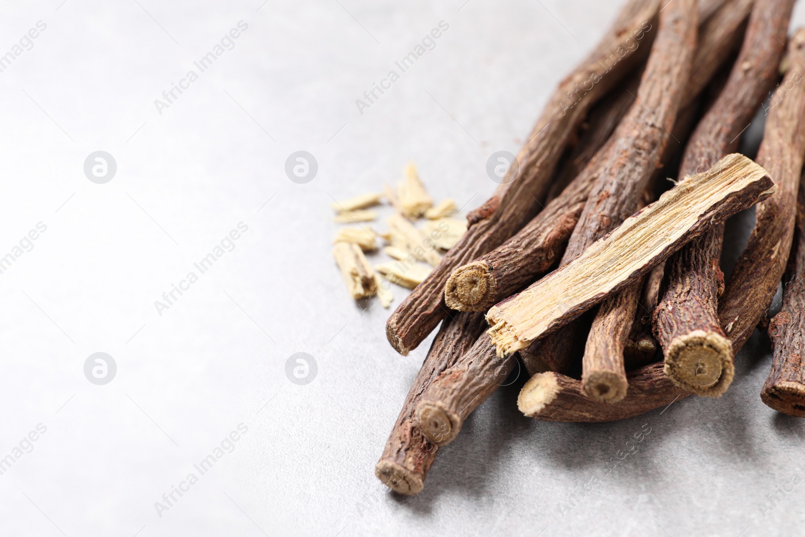 Photo of Dried sticks of liquorice root on grey table, closeup. Space for text