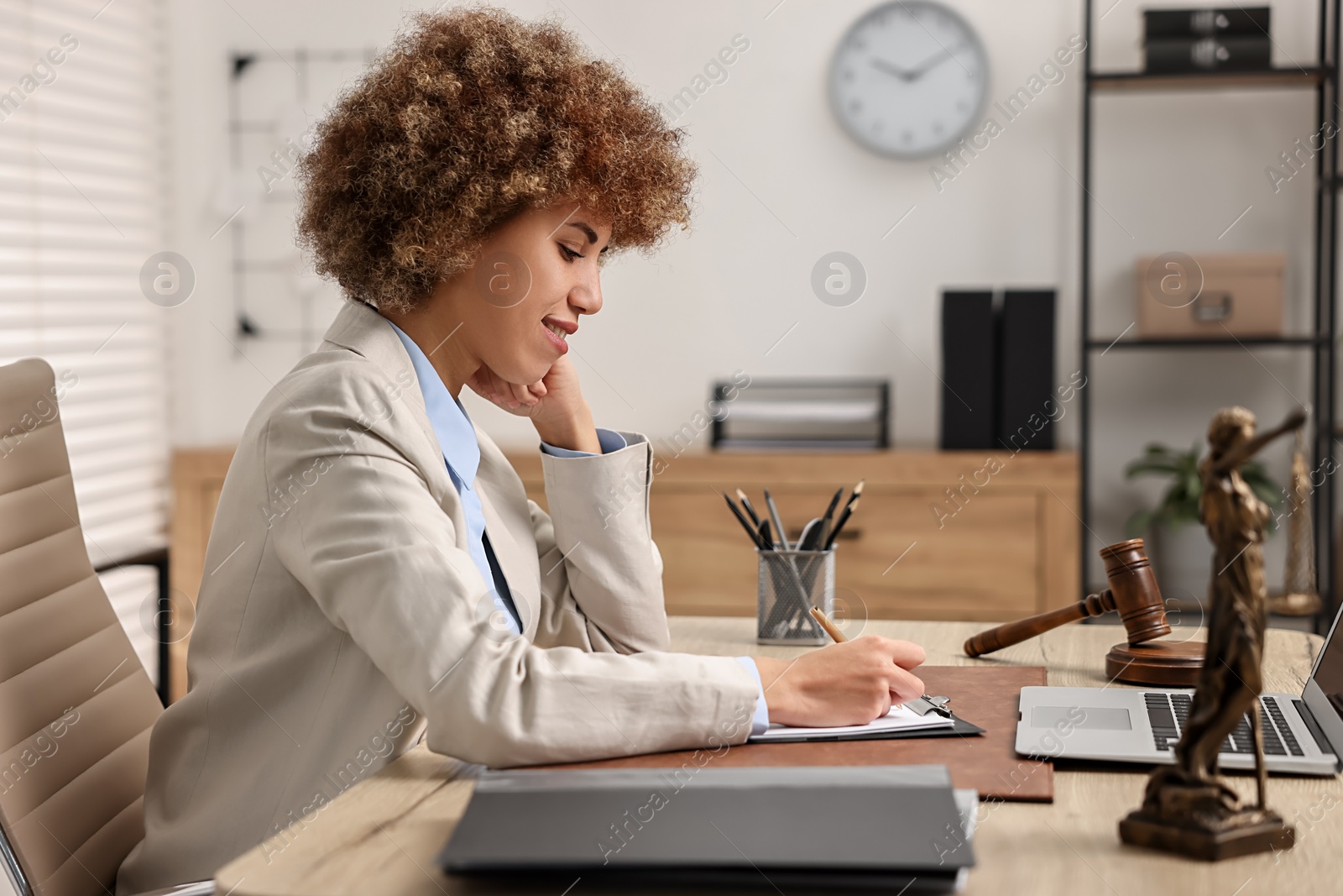 Photo of Notary with clipboard writing notes at workplace in office