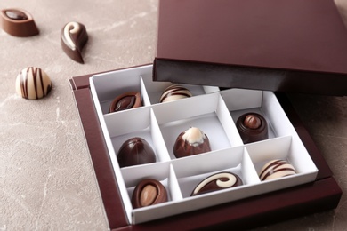 Photo of Box with different tasty chocolate candies on table