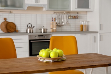 Table with ripe apples in stylish kitchen interior