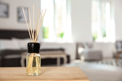 Photo of Aromatic reed air freshener on table indoors