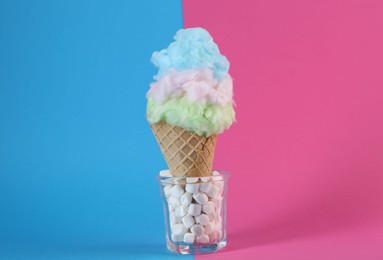 Sweet cotton candy in waffle cone on color background