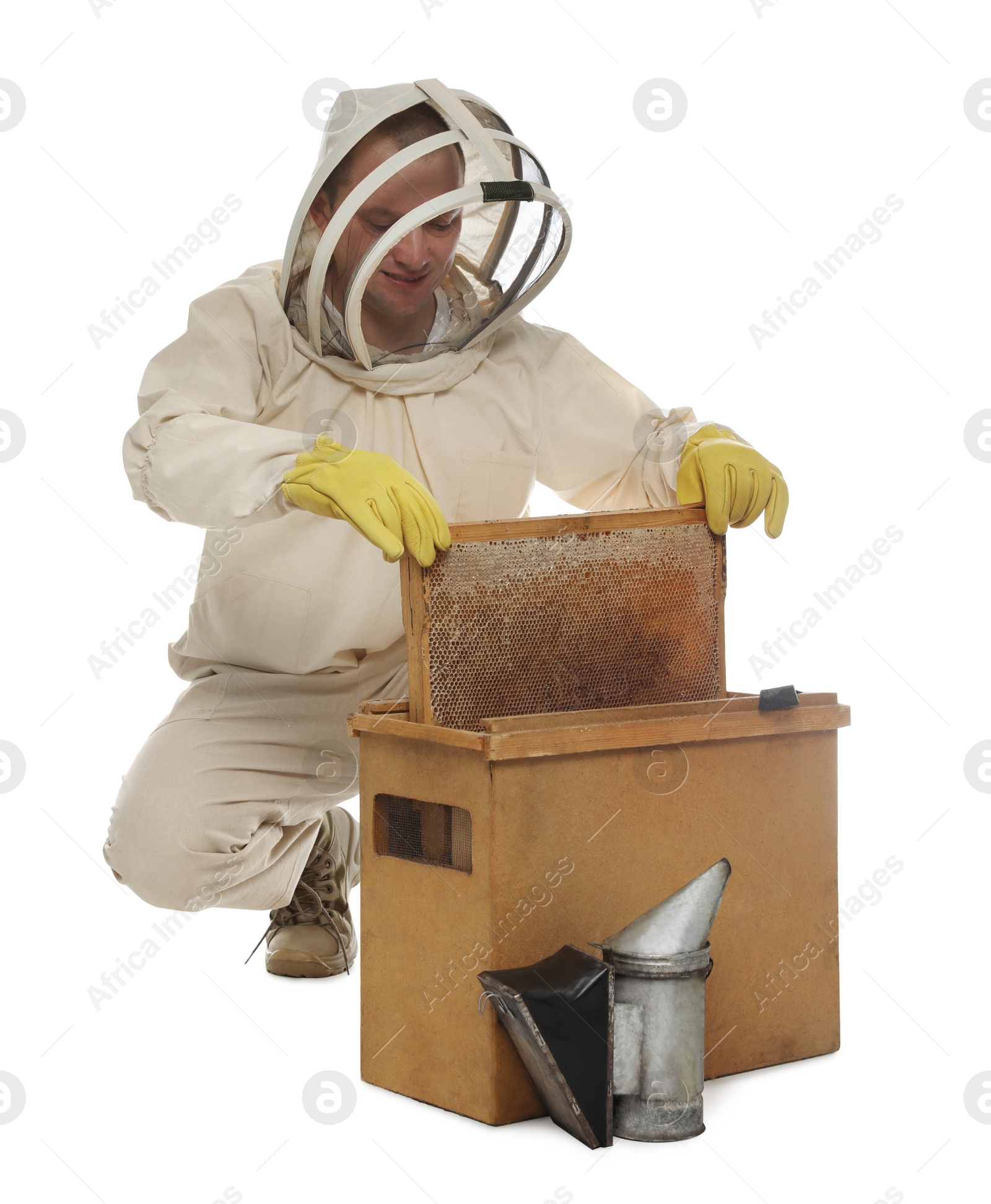 Photo of Beekeeper in uniform taking frame with honeycomb out of wooden hive on white background