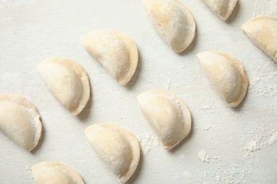 Photo of Raw dumplings on light background, top view. Process of cooking