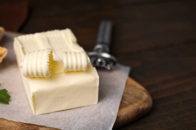 Photo of Tasty butter and spoon on wooden table, closeup. Space for text