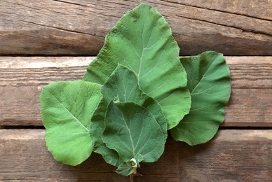 Fresh green burdock leaves on wooden table, flat lay