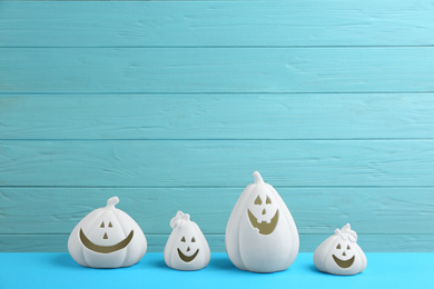 White pumpkin shaped candle holders on light blue table. Halloween decoration