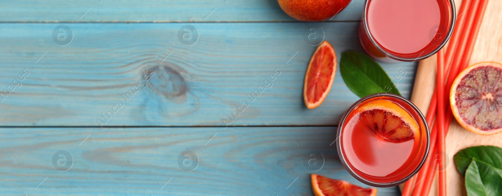 Image of Tasty sicilian orange juice and fruits on light blue wooden table, flat lay with space for text. Banner design