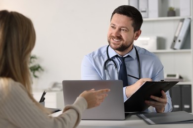 Professional doctor working with patient at white table in hospital