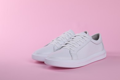 Photo of Pair of stylish white sneakers on pink background