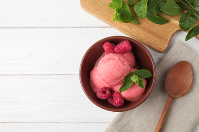 Photo of Delicious pink ice cream served with raspberries and mint in bowl on white wooden table, flat lay. Space for text