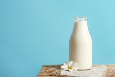 Bottle of milk on table against color wall