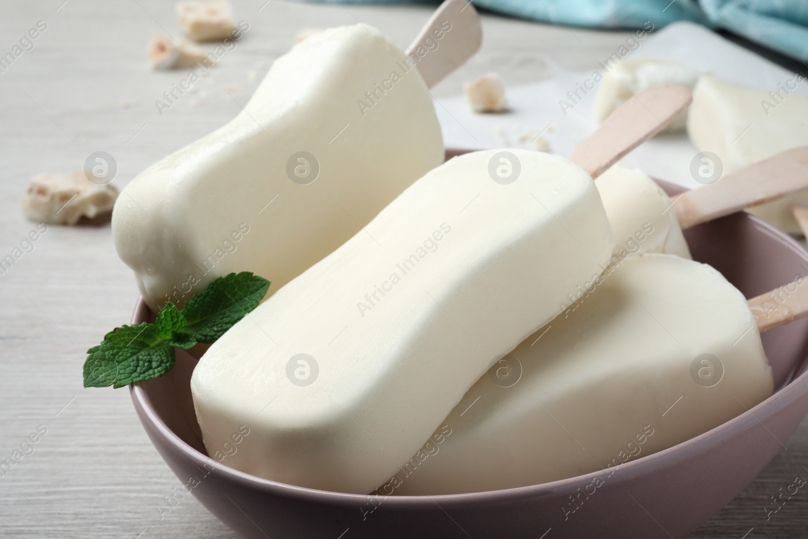 Photo of Delicious glazed ice cream bars and mint on white wooden table, closeup