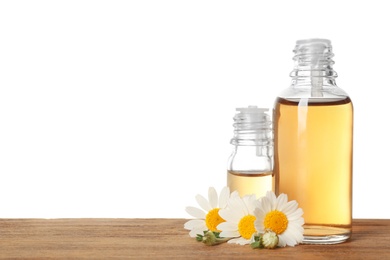 Chamomile flowers and cosmetic bottles of essential oil on wooden table against white background. Space for text