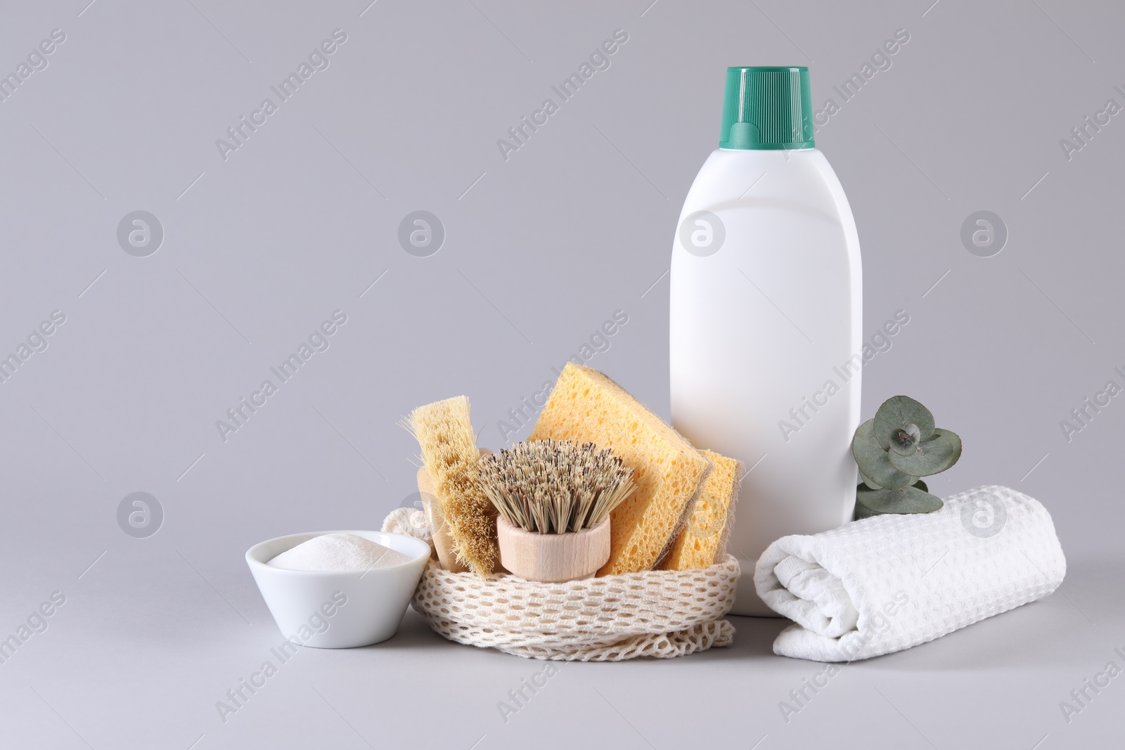 Photo of Bottles of cleaning product, sponges, brushes, rag and baking soda on light background. Space for text