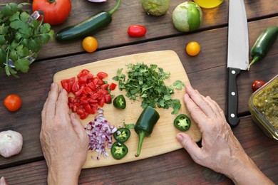 Photo of Woman preparing tasty salsa sauce at wooden table, above view